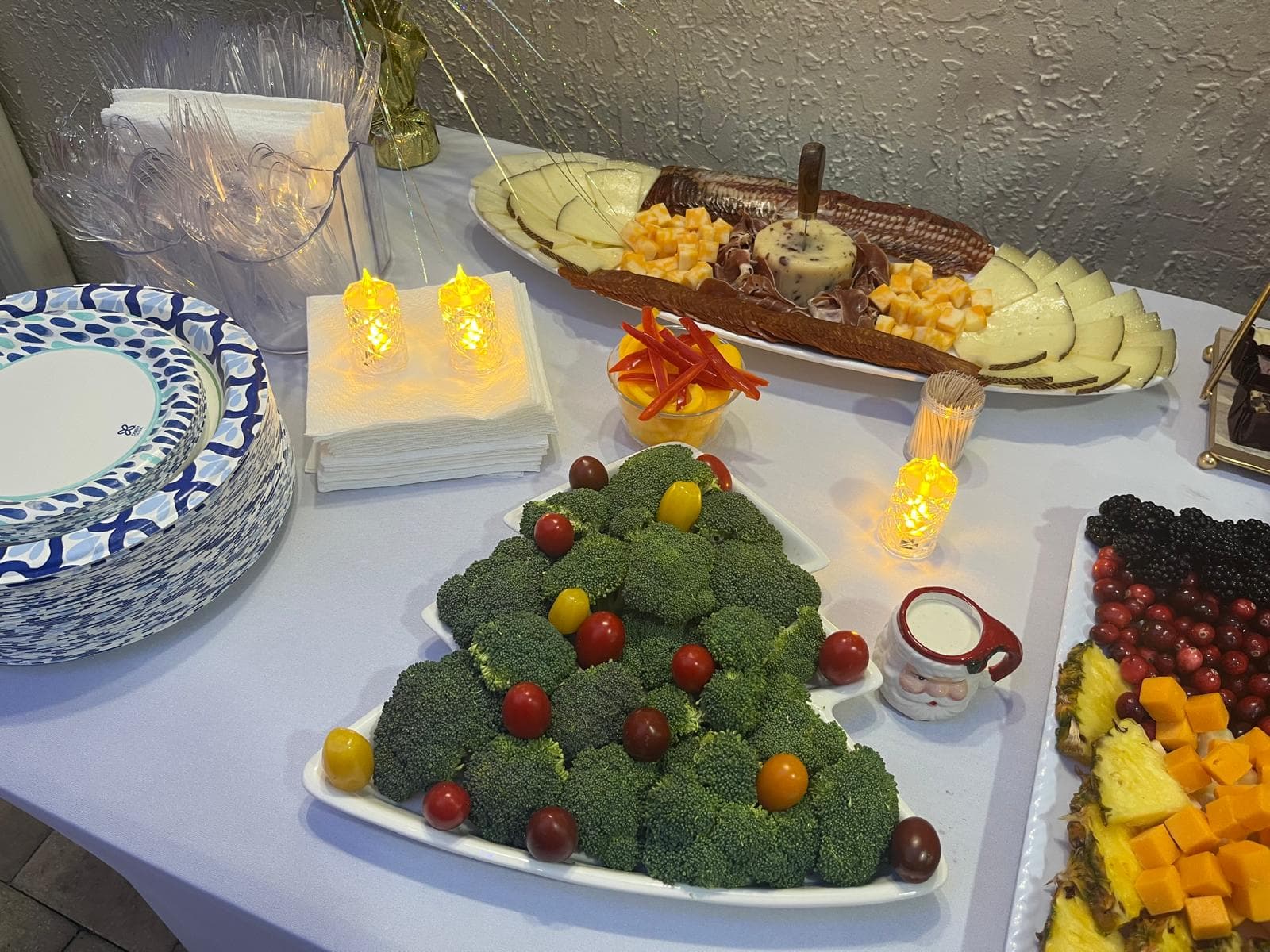 Holiday appetizer table with a broccoli Christmas tree veggie platter and a charcuterie board