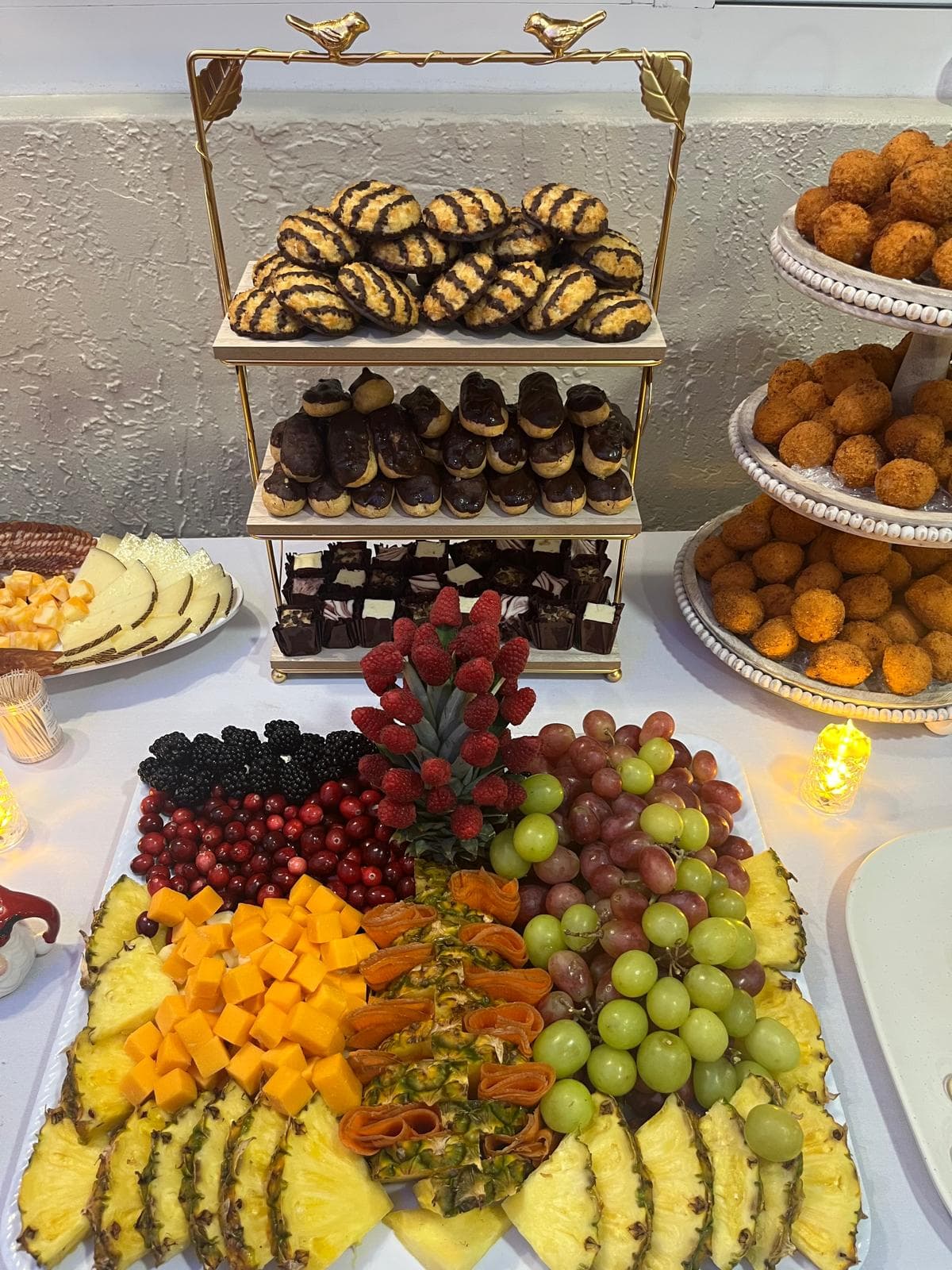 Dessert tower of coconut macaroons, chocolate-dipped cream puffs and truffles beside a fresh fruit platter