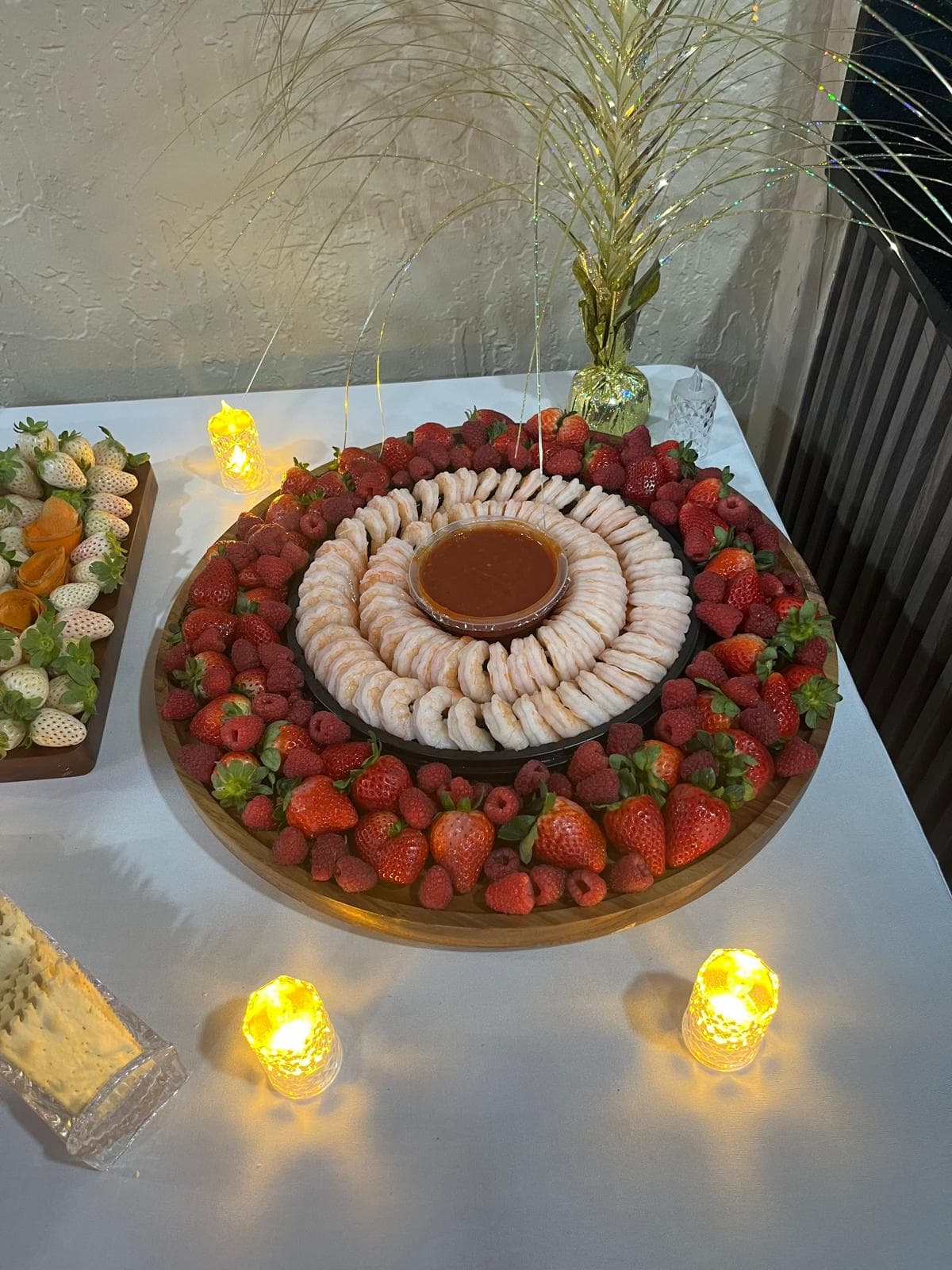 Shrimp cocktail ring with cocktail sauce surrounded by strawberries and raspberries