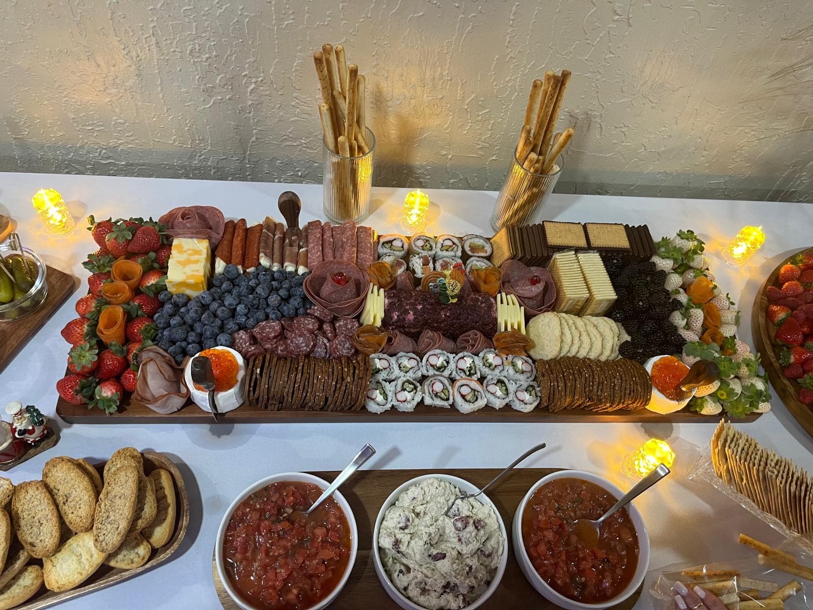 Long charcuterie board with sushi rolls, cured meats, cheeses and fresh berries