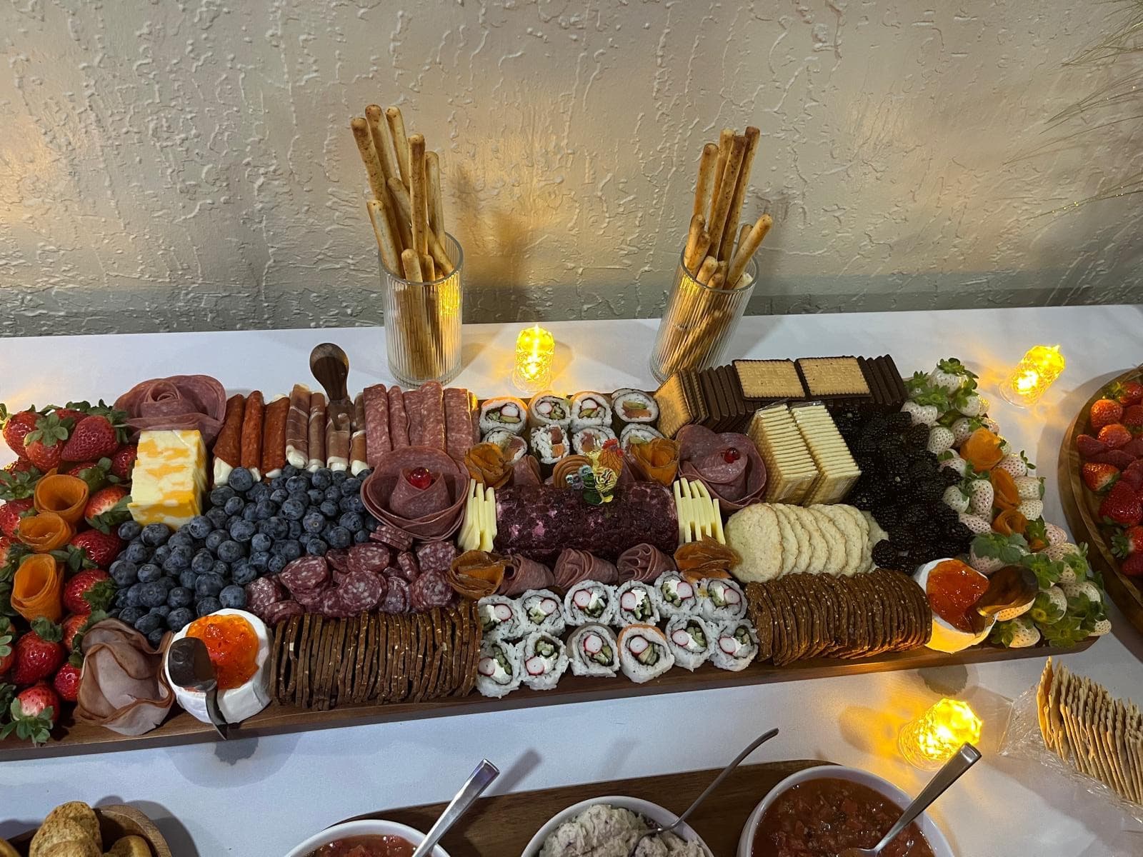 Overhead view of a charcuterie board loaded with sushi rolls, meats, cheese and fruit