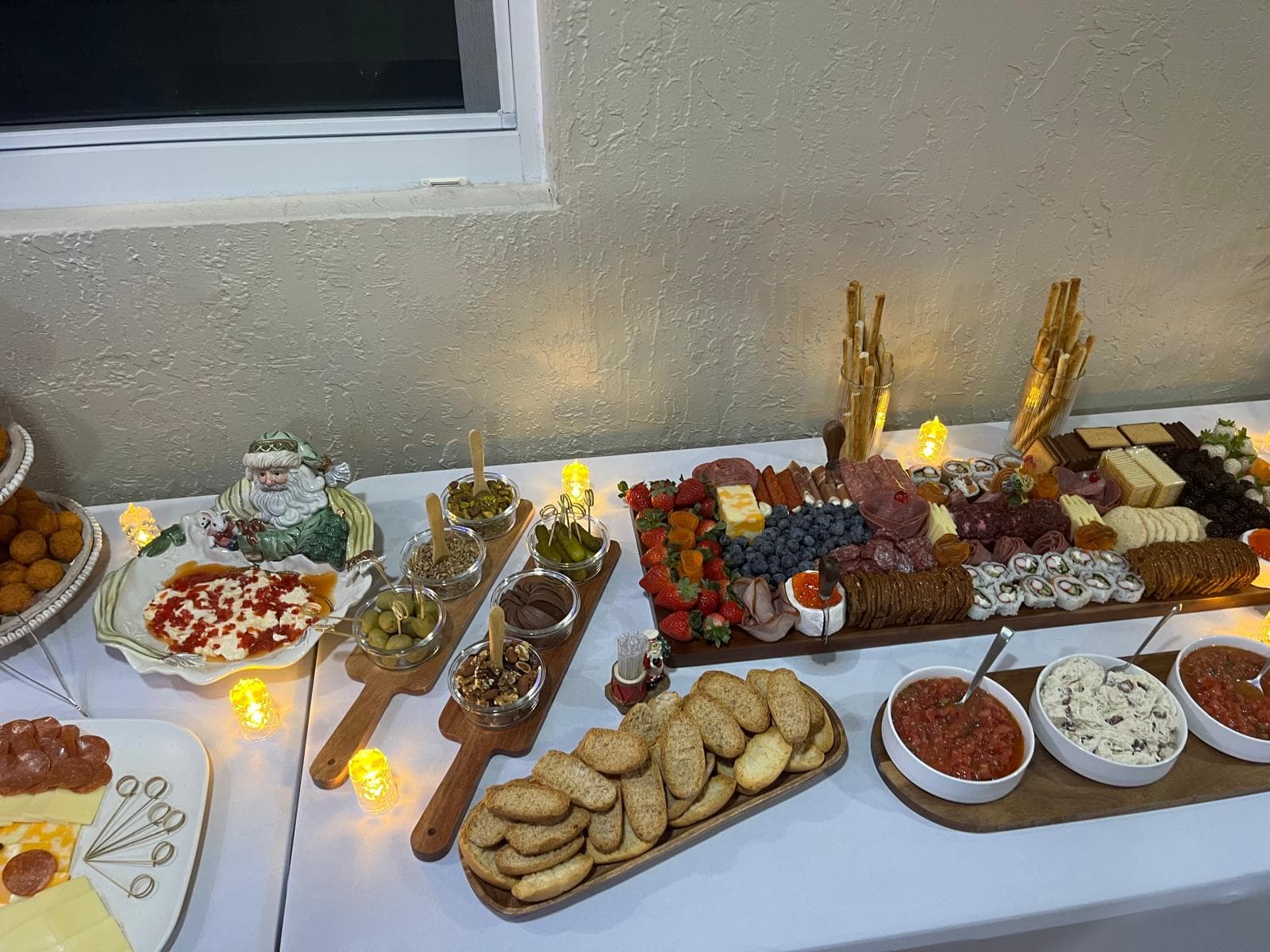 Catering table with a long charcuterie board, dips and toasted bread