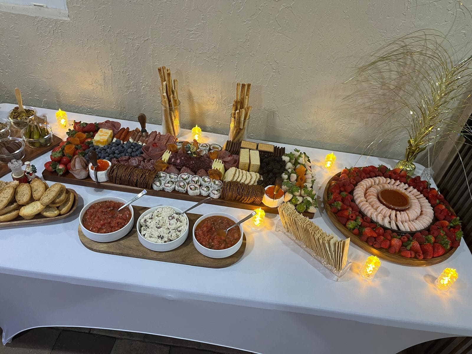 Catering table with a charcuterie board, dips and a shrimp cocktail ring