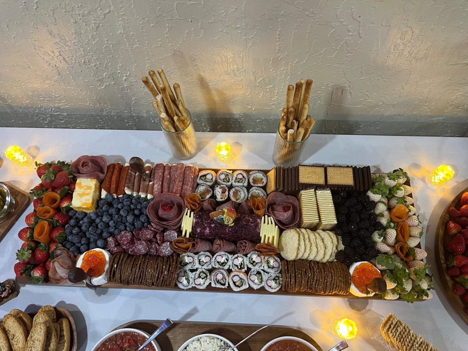 Overhead view of a charcuterie board with sushi rolls, meats, cheese and berries