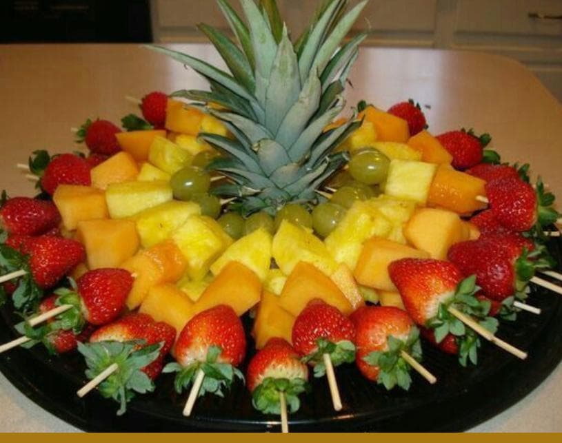 Fruit skewer platter of strawberries, cantaloupe, pineapple and grapes with a pineapple centerpiece