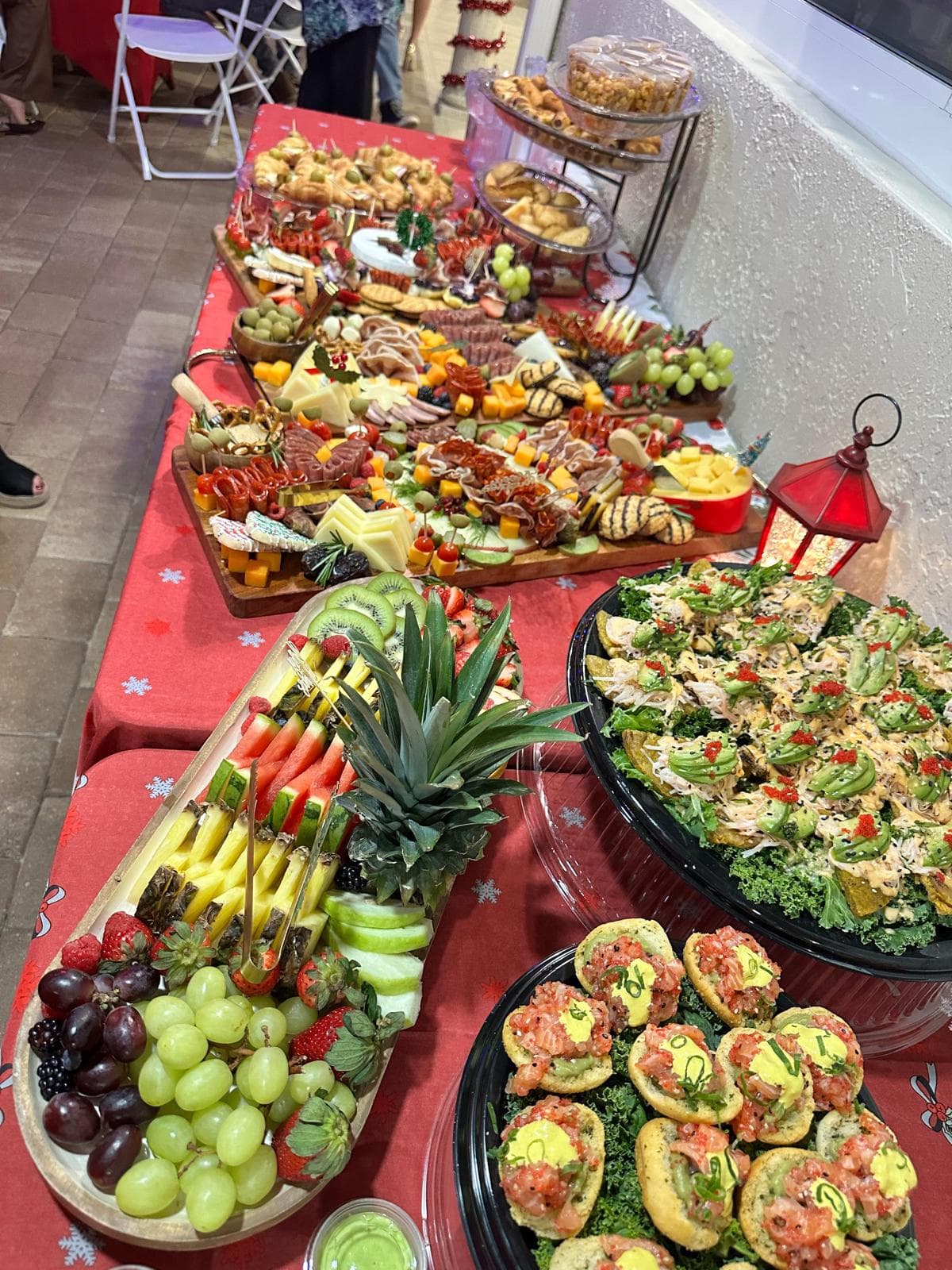 Wide view of a Christmas catering spread with a fruit platter, charcuterie boards and appetizers